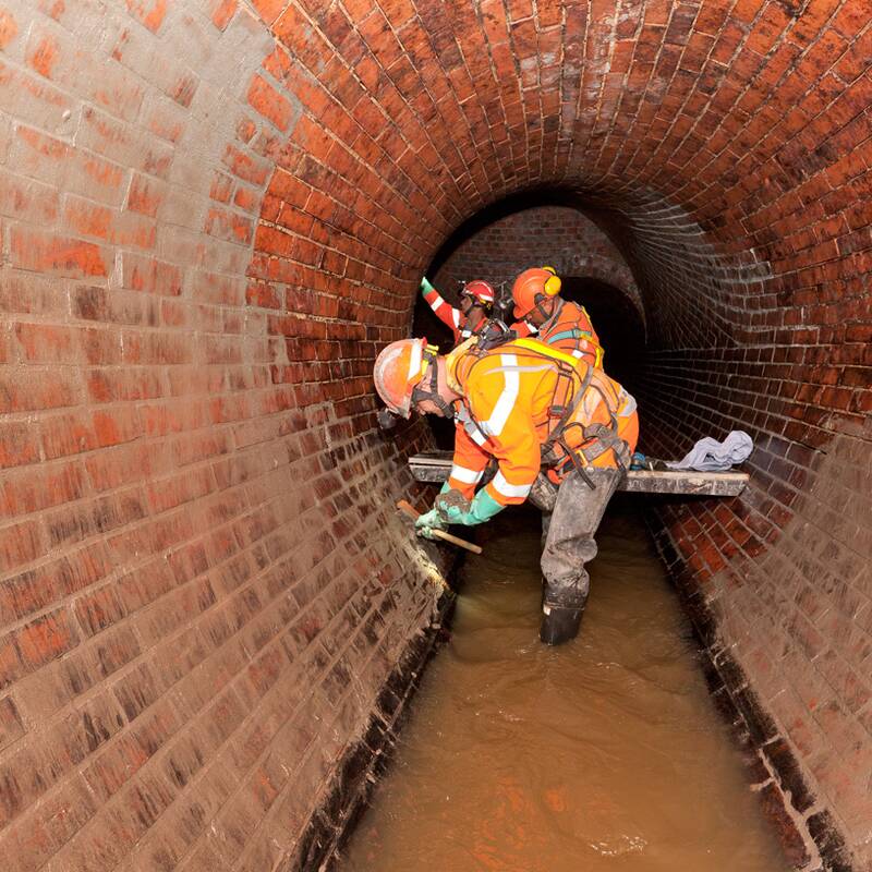 Männer arbeiten in einem Kanal